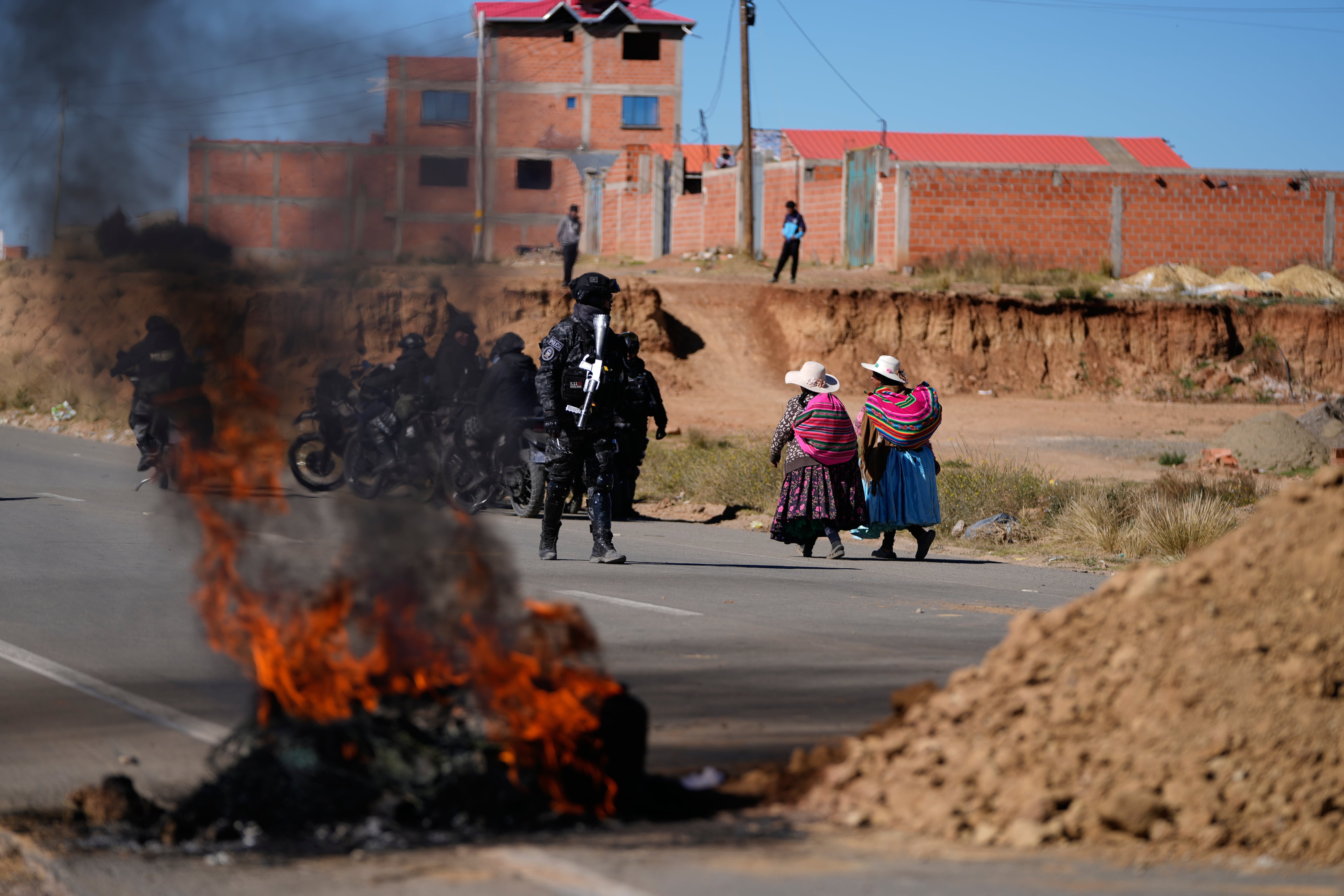 Residentes pasan junto a la policía cerca de barricadas levantadas por manifestantes antigubernamentales en una carretera en El Alto