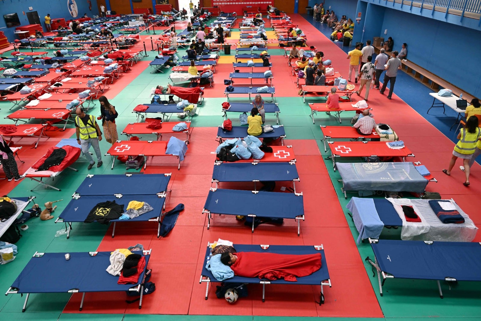 Personas evacuadas descansan en un pabellón deportivo de Villaviciosa de Odón, a 20 km al oeste de Madrid, el 25 de julio de 2026, en medio de incendios forestales que han arrasado hasta 25.000 hectáreas. Los bomberos españoles esperaban controlar el sábado los incendios que se propagaban cerca de Madrid, pero un funcionario advirtió que los vientos erráticos amenazaban con avivar aún más las llamas. Los peores incendios forestales en la historia de la región de Madrid avanzan al oeste de la capital española, obligando a las autoridades a evacuar a unas 60.000 personas o a ordenarles que permanezcan en sus hogares. (Foto de JAVIER SORIANO / AFP)