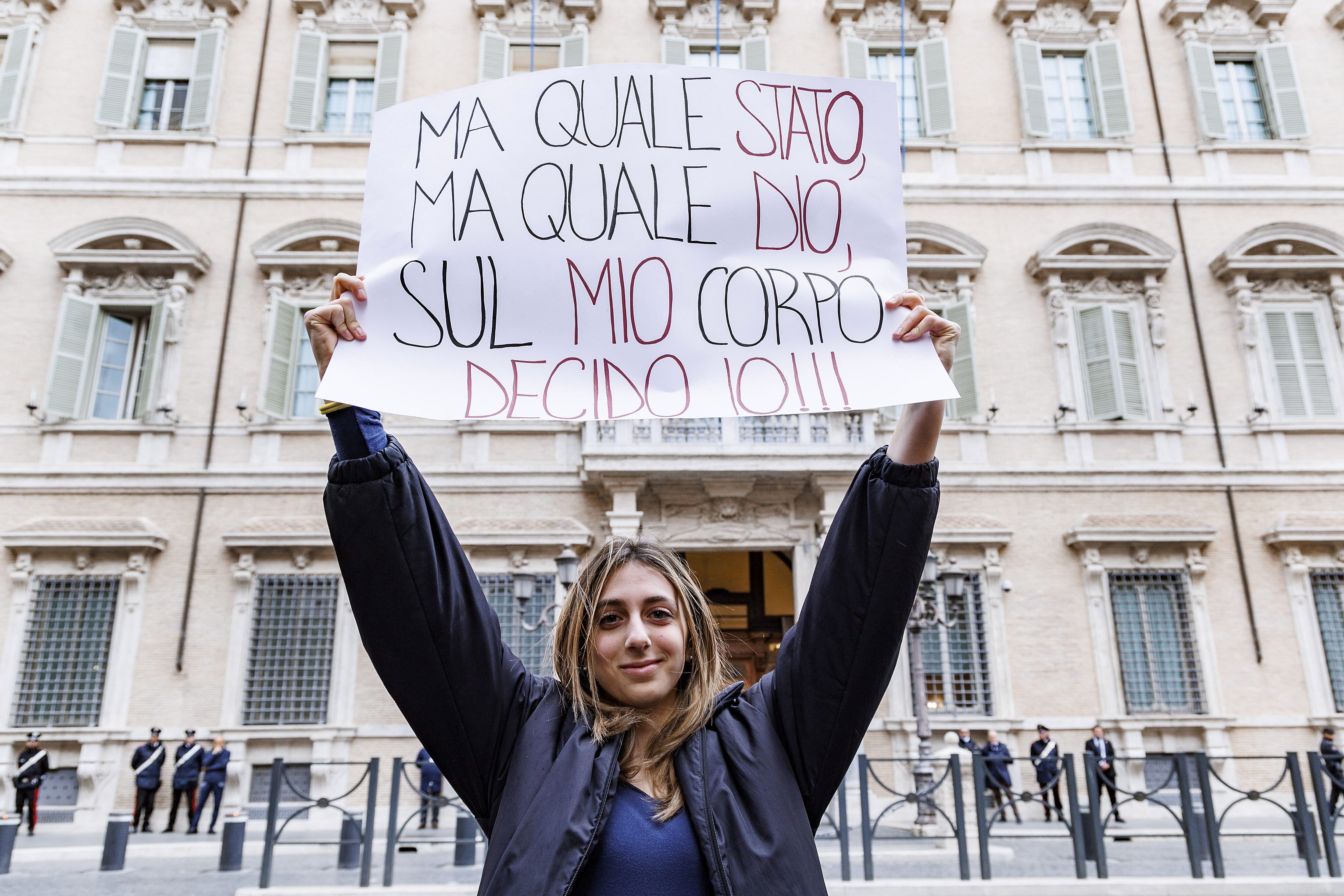 Una mujer sostiene un cartel en italiano que dice 