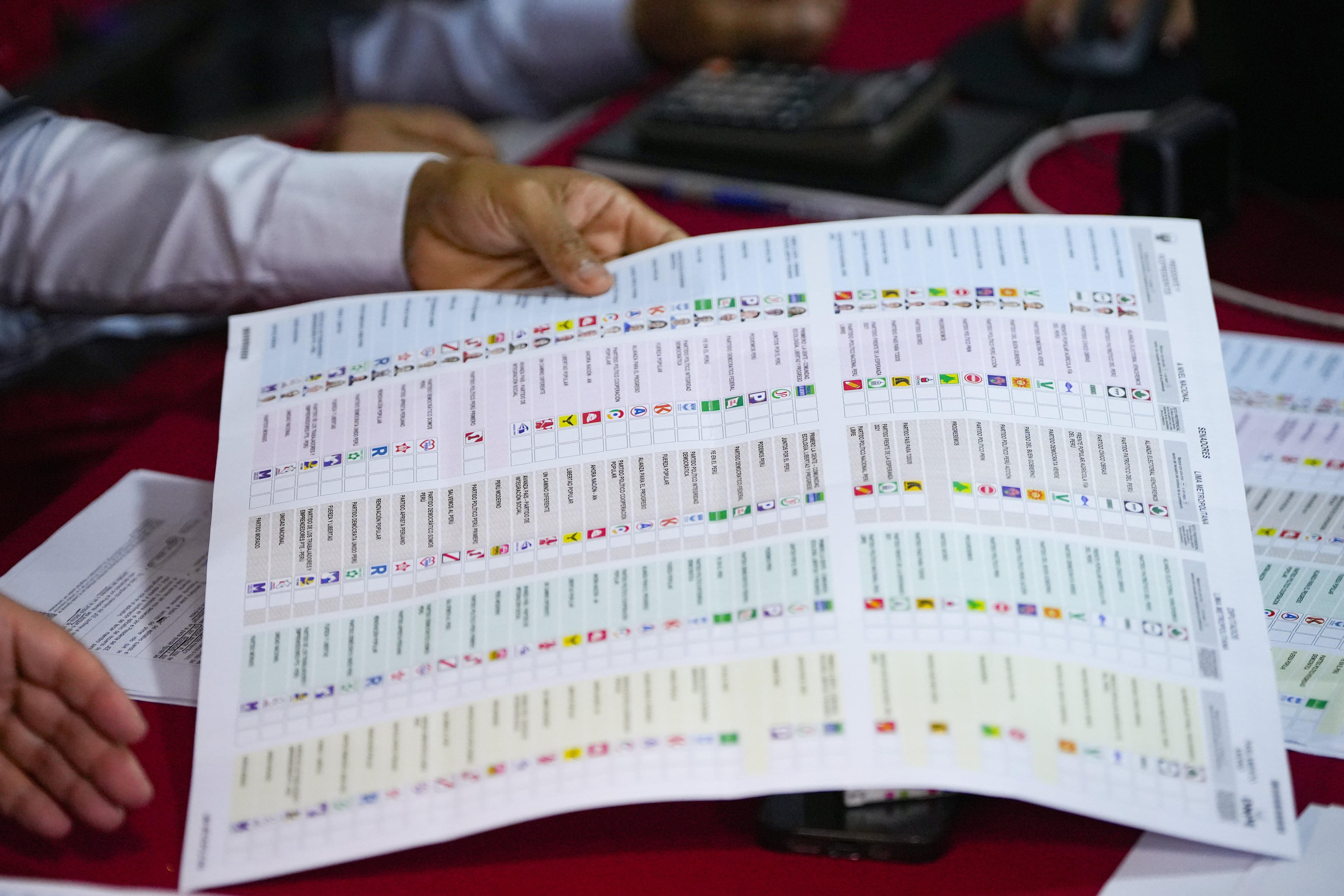 Un miembro designado por el Jurado Electoral Especial analiza una papeleta durante un recuento de votos de las elecciones generales en Lima, Perú