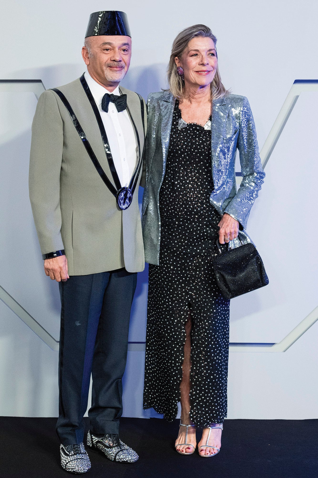 Al elegante vestido negro con lunares blancos que simulaban constelaciones de Chanel, Carolina le agregó una chaqueta metalizada para elevar más la impronta futurista de su estilismo. A su lado, el diseñador de zapatos Christian Louboutin –a cargo de la dirección artística–, con un look de alto impacto galáctico de su propia creación