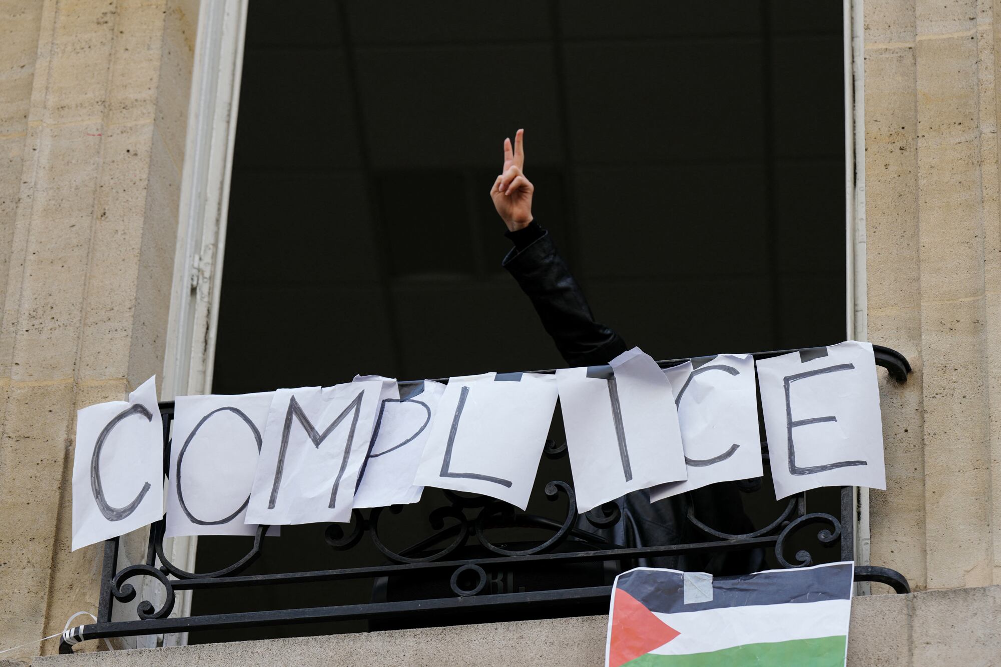 Un manifestante hace el signo de la victoria frente a un cartel que dice 