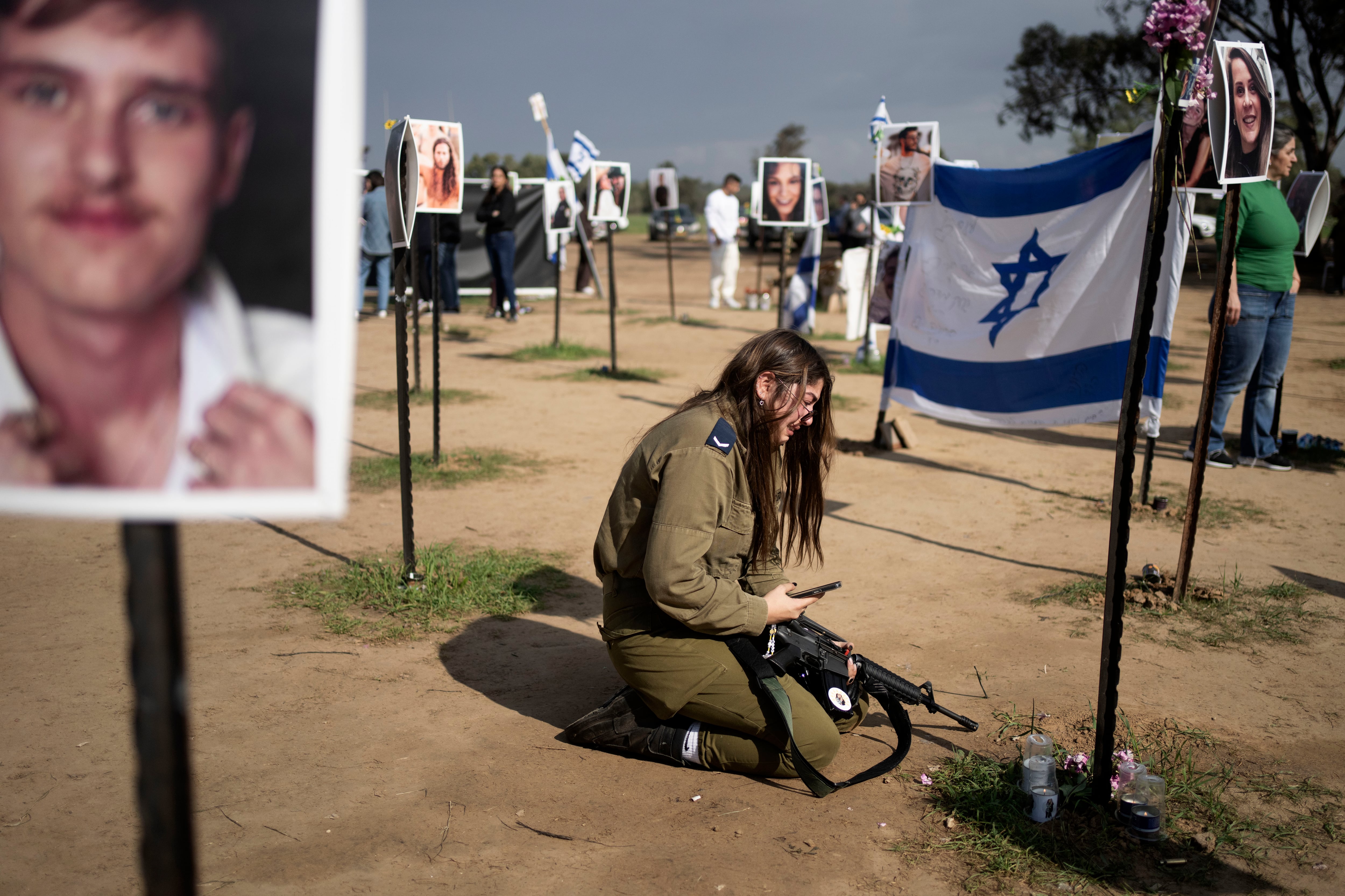 Una soldado israelí llora junto a un cartel que recuerda a una persona secuestrada el 7 de octubre en el ataque transfronterizo de Hamas, en el sur de Israel