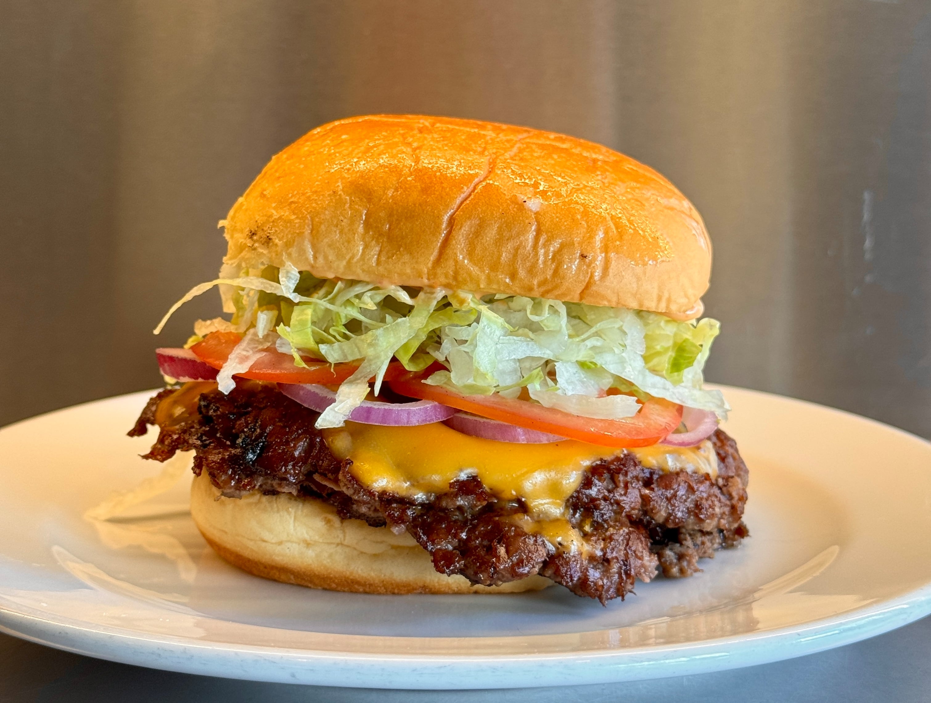 La Clásica de Grasa con medallón smash simple o doble, cheddar, lechuga, tomate, cebolla y salsa de la casa