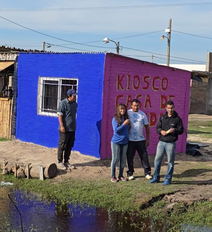 Diego junto a los dueños de un kiosco que pintó.