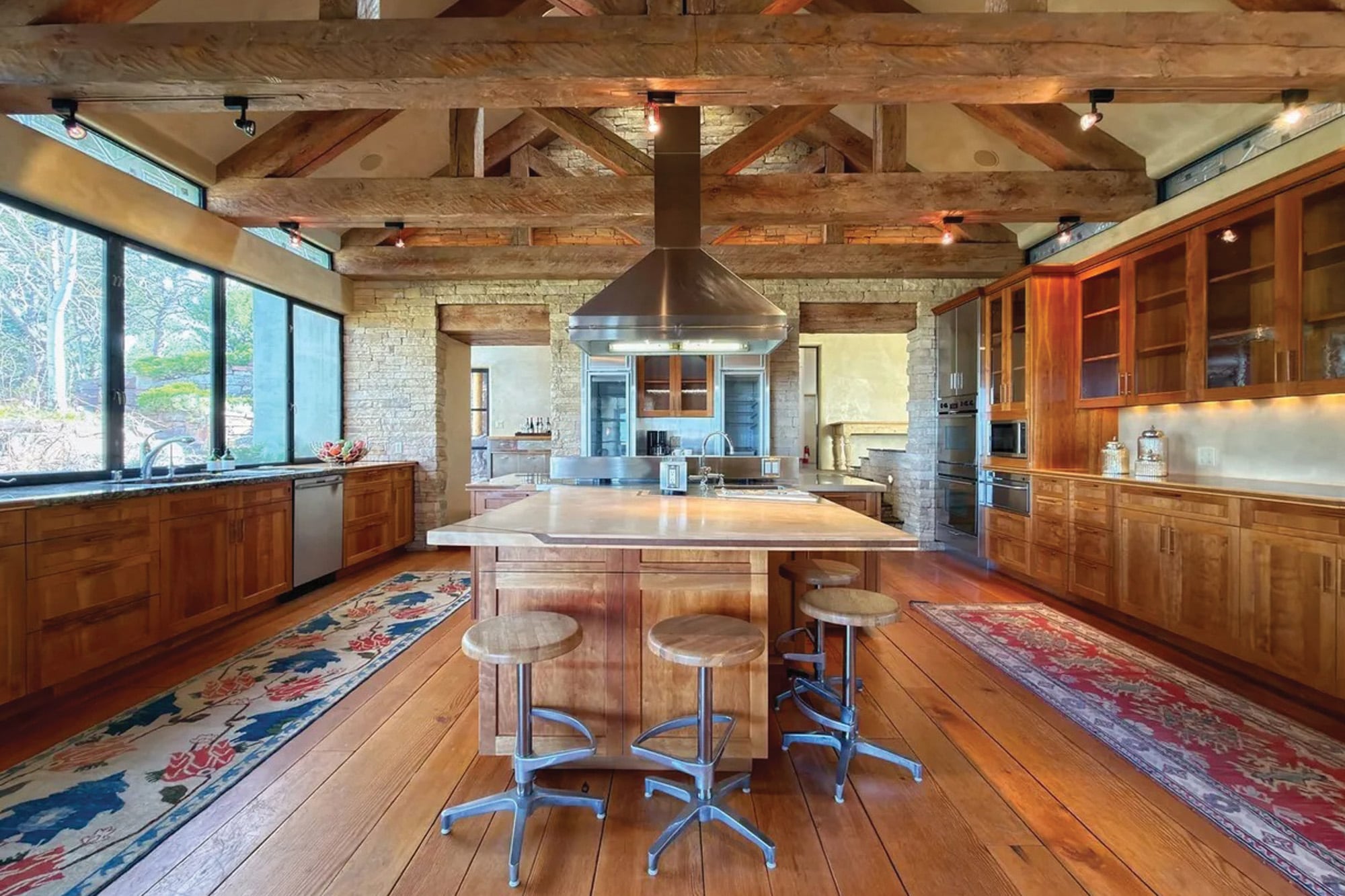 La amplia cocina es fiel al estilo de toda la propiedad: ventanas de estilo industrial que contrastan con las paredes revestidas en piedra y las vigas de madera a la vista