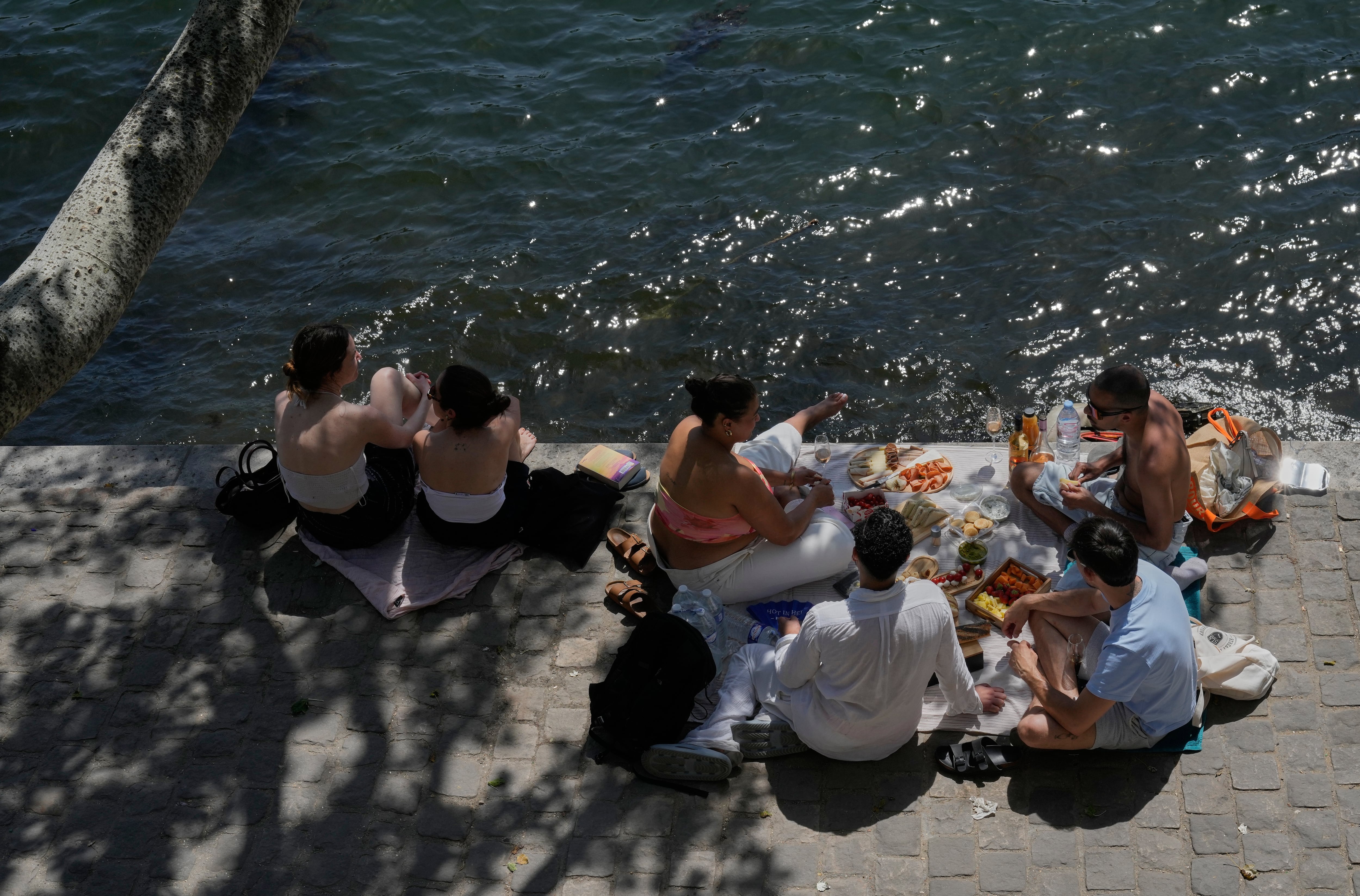 Varias personas disfrutan de un picnic a orillas del río Sena durante un día soleado, el lunes 25 de mayo de 2026, en París