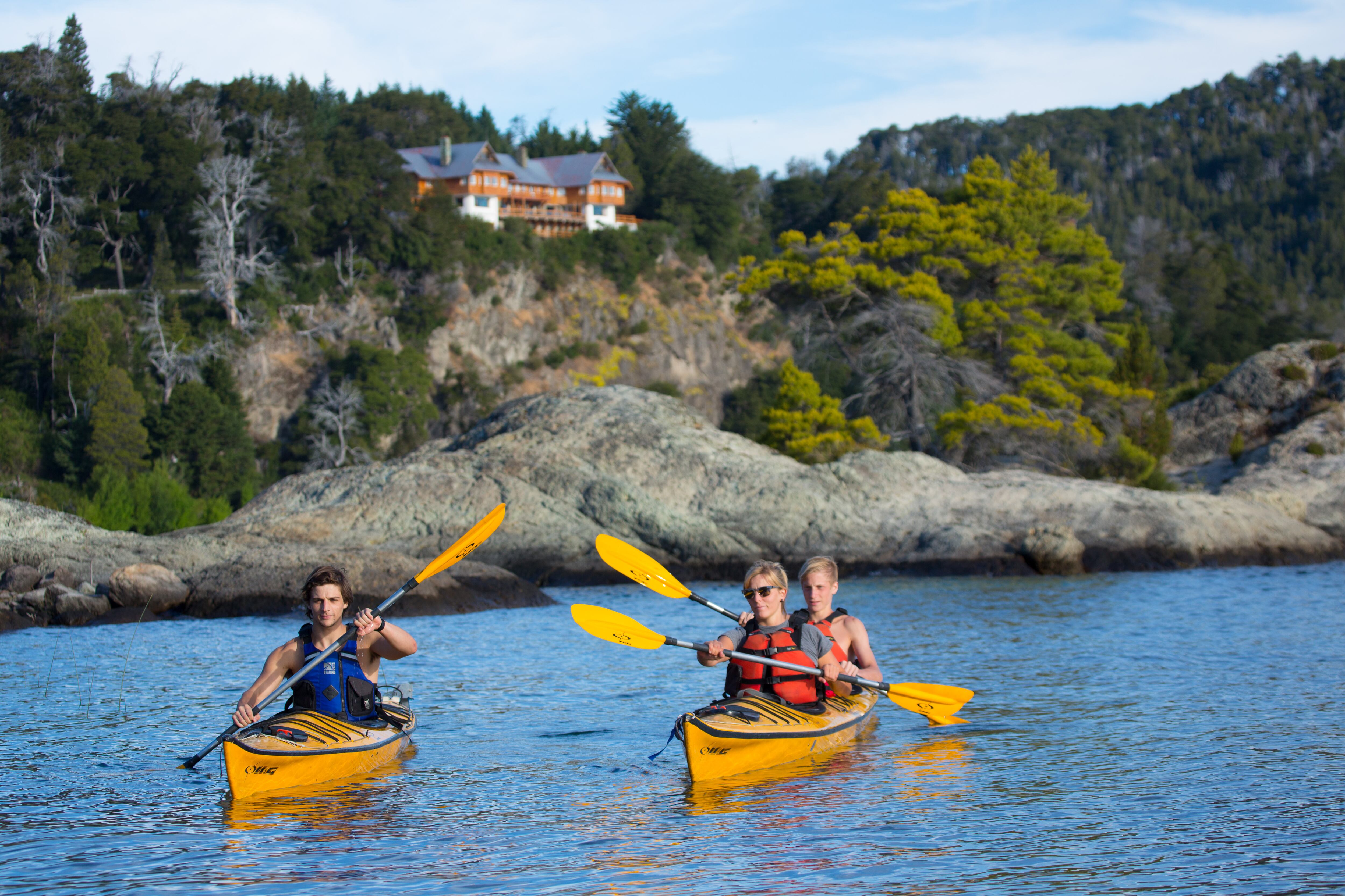 Kayak en el lago Nahuel Huapi, con la hostería de fondo.