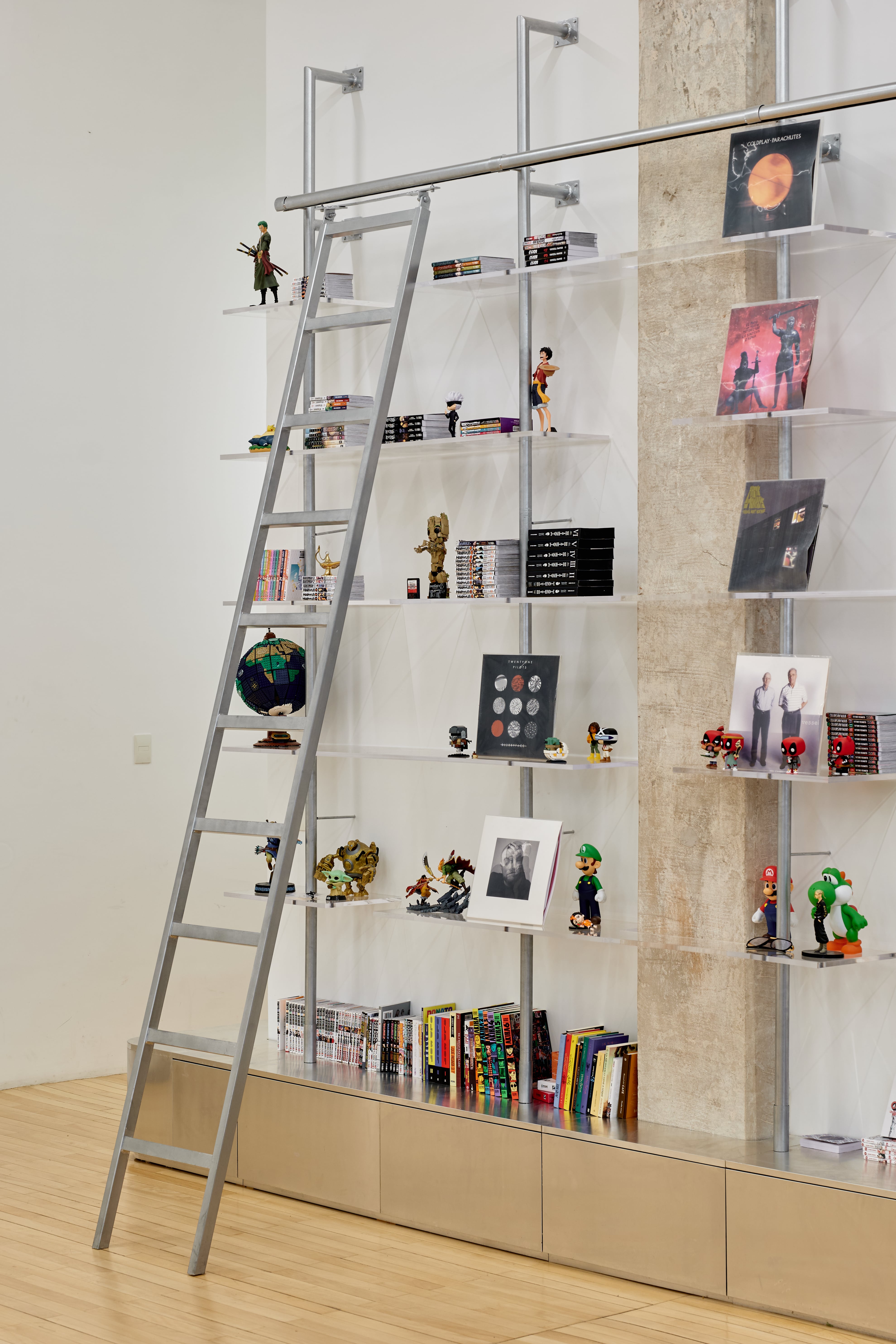 Biblioteca de caños de acero, estantes de acrílico y rack inferior de MDF enchapado en aluminio (Wollstudio).
