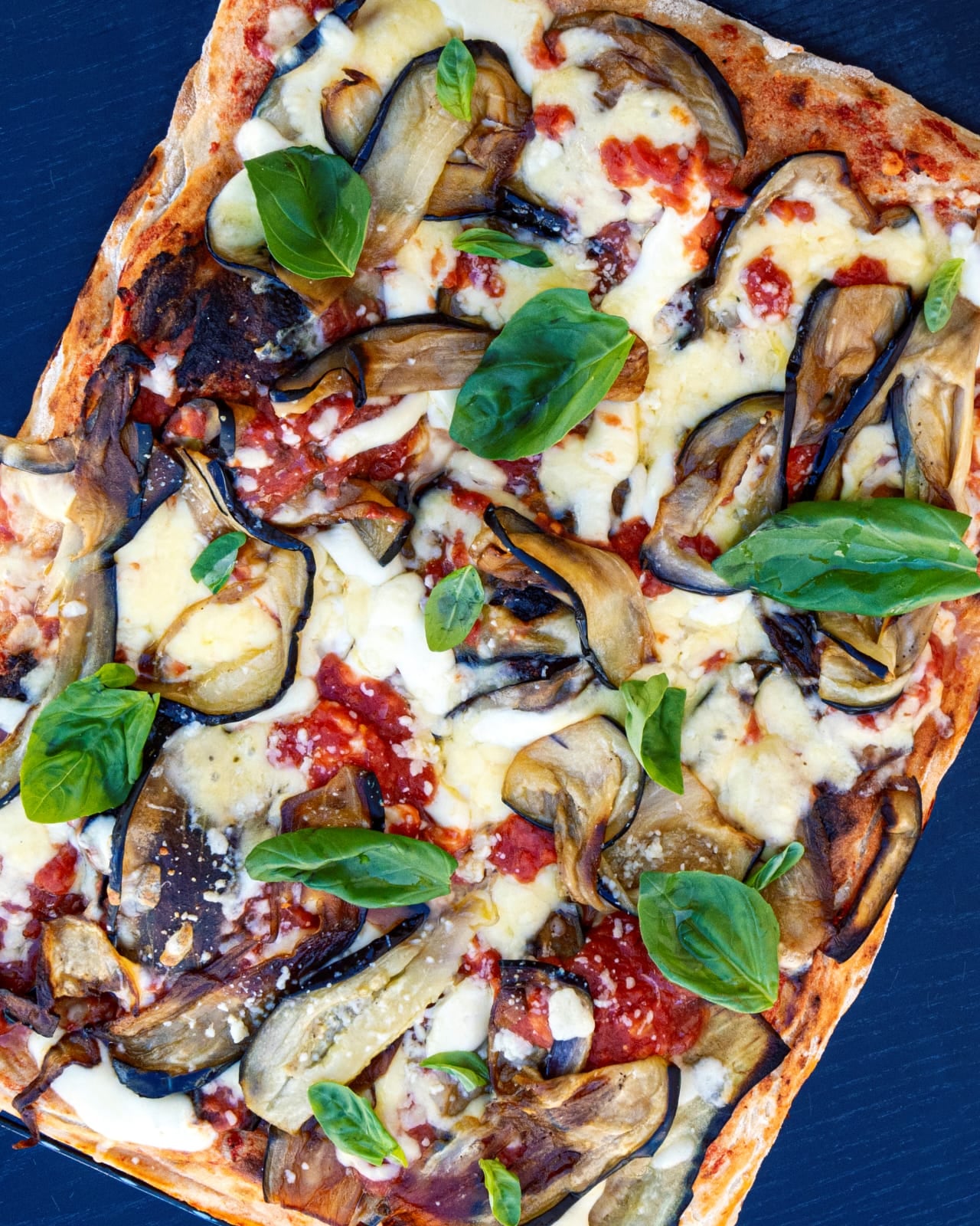 Pizza base parmigiana di melanzane, fior di latte, pomodoro, parmigiano y albahaca