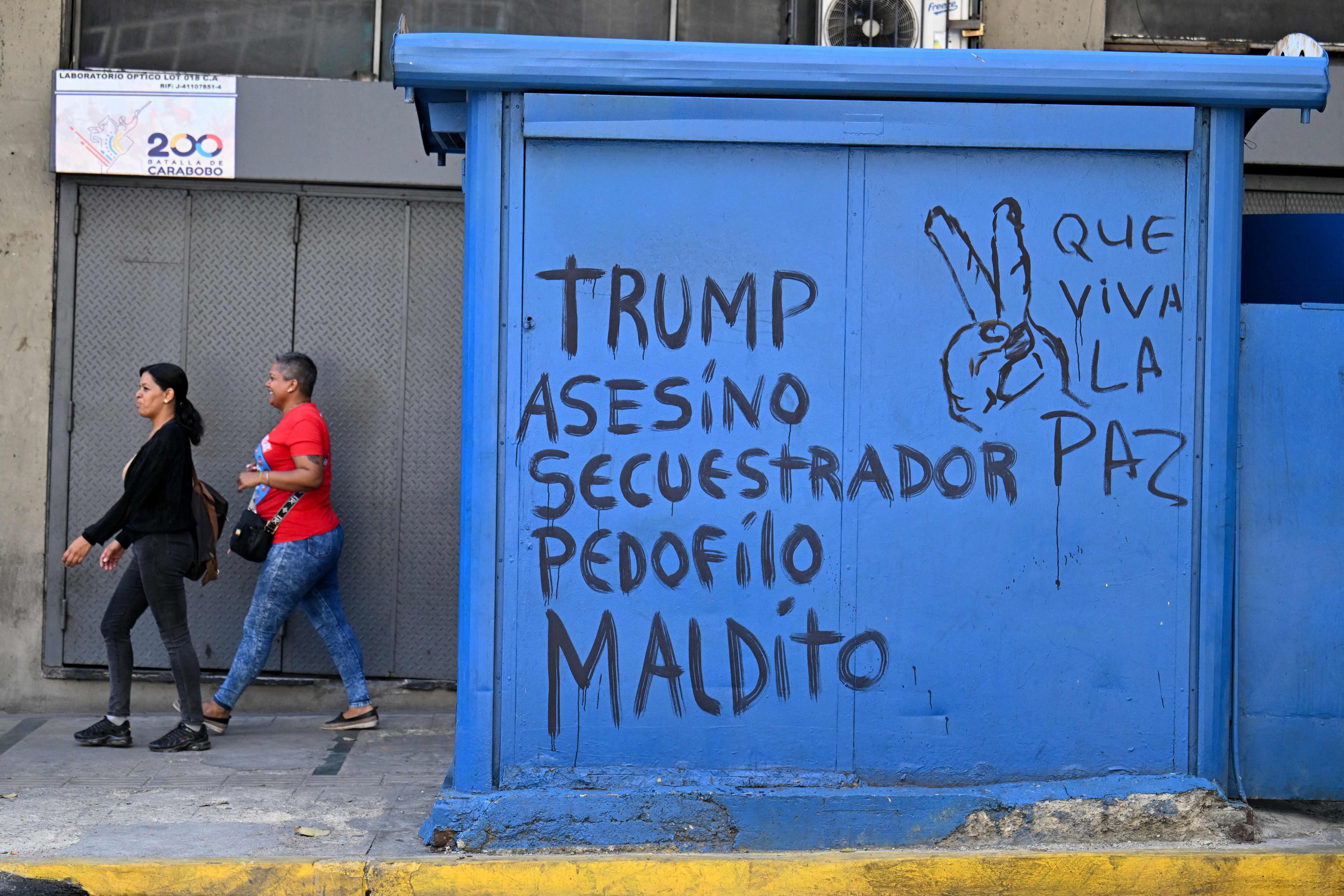 Mujeres caminan junto a un grafiti contra el presidente de Estados Unidos, Donald Trump, en Caracas, el 5 de enero de 2026