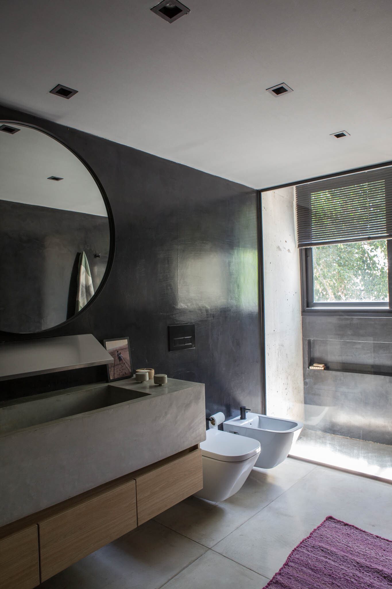 En el baño en suite, bacha de hormigón pulido hecha en obra. Vanitory (Cantersfont). Espejo circular (Vetromile Vidrios). Revestimiento en microcemento negro (Quimtex). Sanitarios ‘The Gap’ (Roca).