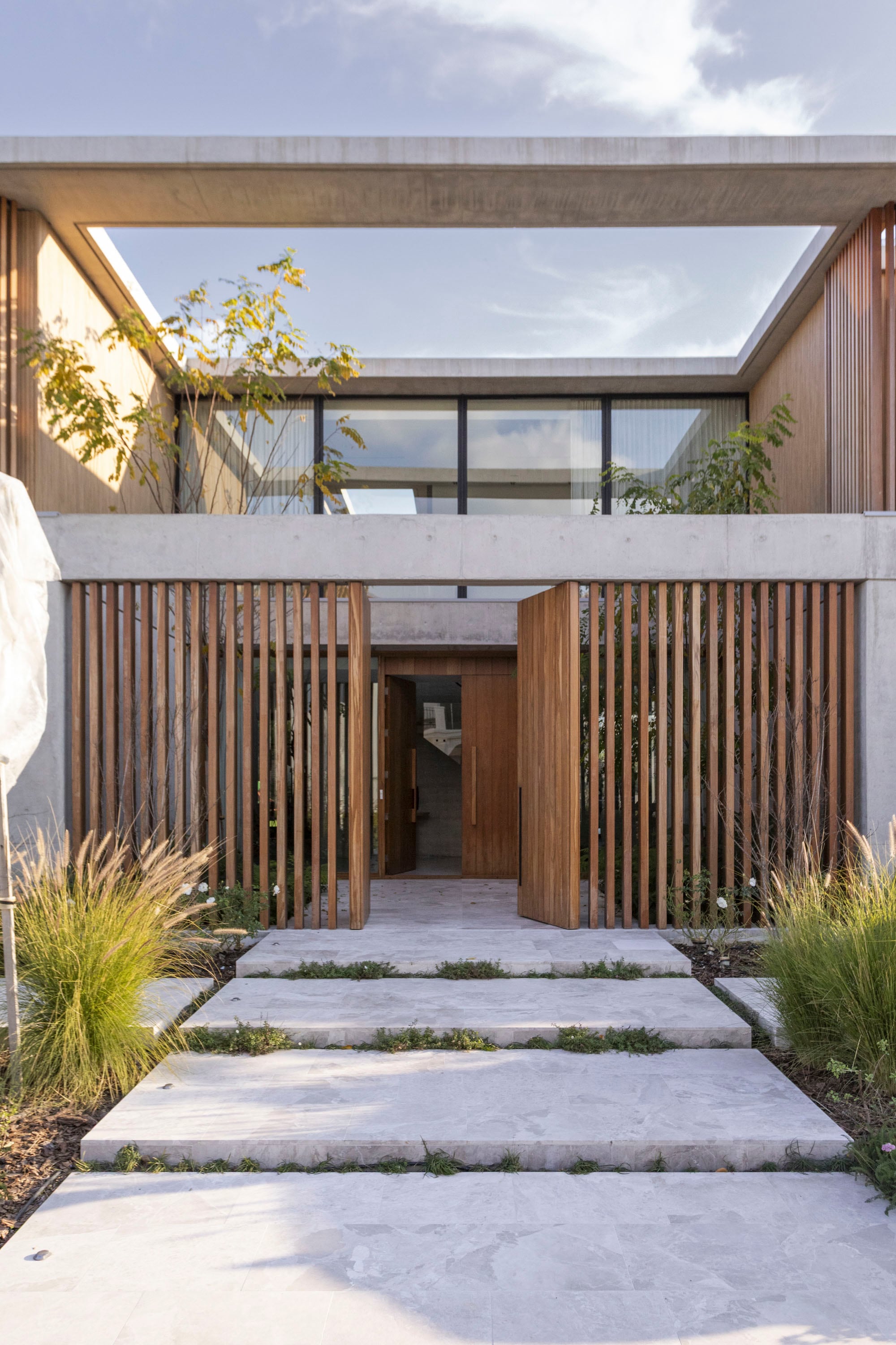 La fachada con madera, vidrio y hormigón anticipa la síntesis de elementos del interior, una característica que se mantendrá durante todo el recorrido, aportando armonía a esta vivienda proyectada por estudio LAK, del arquitecto Lucas Muñoz.