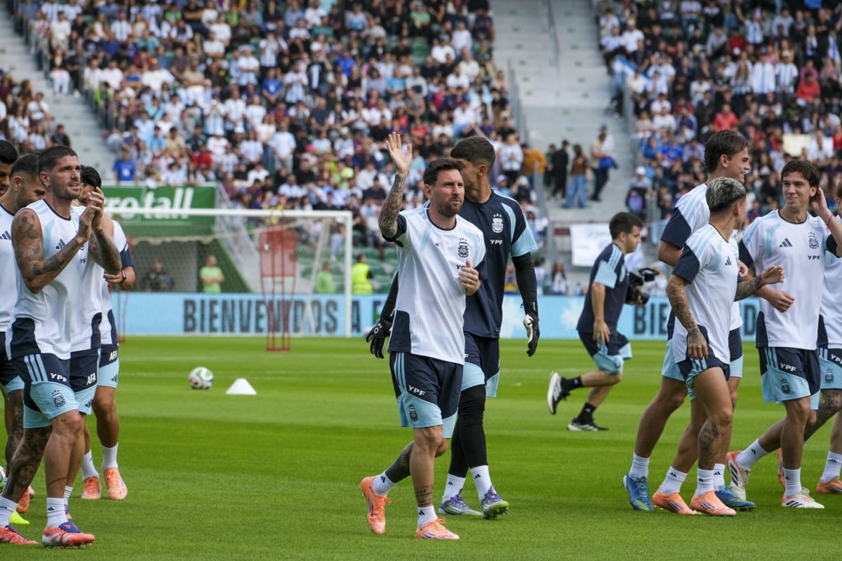 Lionel Messi saluda y Rodrigo De paul aplaude, durante el entrenamiento de la selección argentina en Elche, ante una multitud