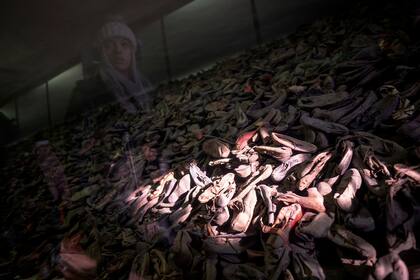 A 75 años de la liberación de los detenidos en Auschwitz, una persona recorra la muestra donde se exhiben zapatos de los prisioneros