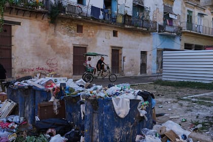 A bicycle taxi driver carries a passenger past trash on a street in Old Havana, Monday, January 5, 2026. (AP Photo/Ramon Espinosa)