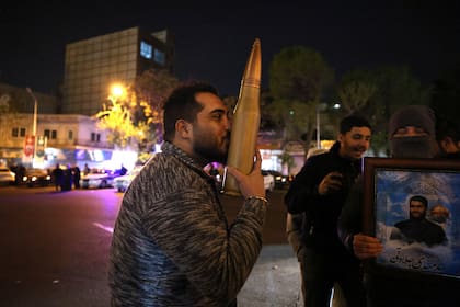 A demonstrator kisses a bullet shell replica as others gather at Palestine Square in Tehran on April 14, 2024, after Iran launched a drone and missile attack on Israel. Iran's Revolutionary Guards confirmed early April 14, 2024 that a drone and missile attack was under way against Israel in retaliation for a deadly April 1 drone strike on its Damascus consulate. (Photo by ATTA KENARE / AFP)