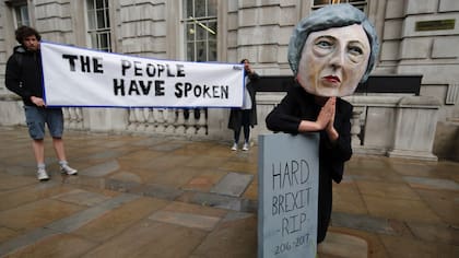 A demonstrator wears a mask depicting Britain&amp;apos;&amp;apos;s Prime Minister and leader of the Conservative Party Theresa May, poses with a mock gravestone bearing the words &quot;Hard Brexit, RIP&quot;, during a protest photocall near the entrance 10 Downing Street in central London on June 9