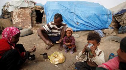 Una familia desayuna junto a su tienda en un campamento de desplazados cerca de Sanaa