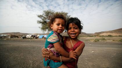 Una niña lleva alzada a su hermana en un campo de refugiados cerca de Sanaa, la capital yemenita