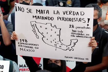 A journalist holds a poster that reads "The killing of periodists doesn't kill the truth" during a demonstration against violence against journalists, especially for the murders of journalists Margarito Martinez and Lourdes Maldonado in Tijuana last week, in Guadalajara, Mexico, on January 25, 2022. - The murders of two journalists in the Mexican border city of Tijuana in less than a week have triggered calls for the government to step up protection of media workers. (Photo by ULISES RUIZ / AFP)