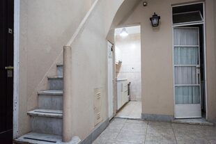 A la izquierda, la escalera que conduce al entrepiso y a la terraza; en el centro de la imagen, una pequeña cocina y, a la derecha, el baño
