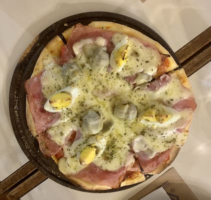 A la Renato: lleva salsa de tomate, mozzarella, rodajas de tomate, jamón cocido, alcauciles y huevo duro.