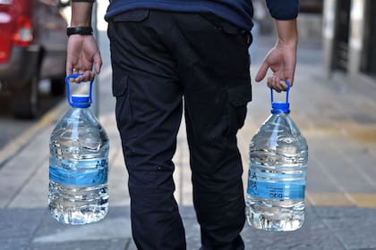 Un hombre lleva dos botellas de agua potable en Montevideo.