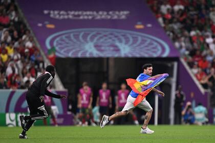 A man (R) invades the pitch holding a LGBT flag as he wears a t-shirt reading "Respect for Iranian woman" during the Qatar 2022 World Cup Group H football match between Portugal and Uruguay at the Lusail Stadium in Lusail, north of Doha on November 28, 2022. (Photo by Kirill KUDRYAVTSEV / AFP)