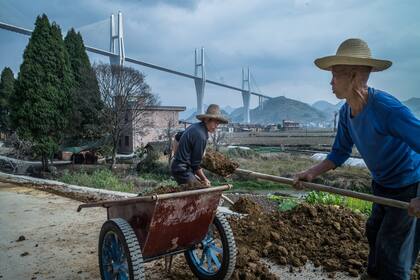 A medida que la economía de China ha crecido en las décadas pasadas, más de 700 millones de personas han salido de la pobreza. Trabajadores cerca del puente de Chishi en Hunan