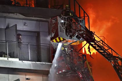 Una persona se encuentra en un balcón esperando ser rescatada por los bomberos mientras un bloque de viviendas arde en Valencia, España, el jueves 22 de febrero de 2024