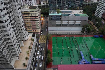 A pesar de la lluvia, los residentes hacen fila para hacerse la prueba en un sitio temporal de pruebas de coronavirus en Hong Kong, el jueves 17 de febrero de 2022. Hong Kong reportó el jueves 6116 nuevas infecciones por coronavirus, ya que los hospitales de la ciudad alcanzaron el 90% de su capacidad y las instalaciones de cuarentena están funcionando. en su límite, dijeron las autoridades. (AP Photo/Kin Cheung)
