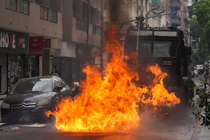 A police water cannon douses a fire sparked by a Molotov cocktail during clashes at a march by trade unions and opposition groups against a labor reform bill proposed by President Javier Milei's government in Buenos Aires, Argentina, Wednesday, Feb. 11, 2026. (AP Photo/Gustavo Garello)
