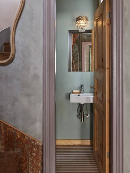 A un costado, un pequeño toilette de 2 m2 completa los servicios sin dejar de jugar con el diseño: baldosas en rosa y hueso, cemento alisado, madera recuperada y luminarias barrocas.