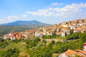 A view on the roofs of old village Ripacandida with old houses on green hill and big mountain Vulture in background. Basilicata South Italy