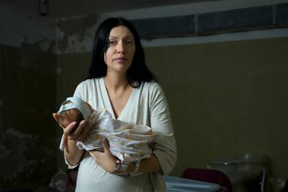 Una mujer, que no quiso ser identificada, posa para una fotografía mientras sostiene a su niña recién nacida en el sótano de un hospital de maternidad convertido en sala médica y utilizado como refugio antiaéreo durante las alertas de ataques aéreos, en Kiev, Ucrania