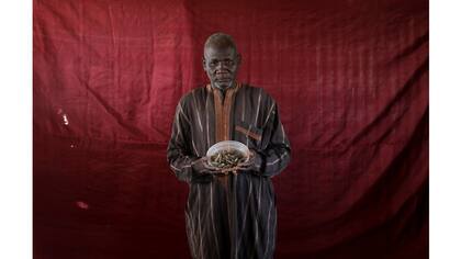 Abdulwahal Abdulla sostiene un tazón de pescado seco de tilapia
