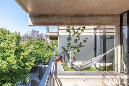 Aberturas de PVC foliado en negro (IWIN Aberturas). La damasca de la terraza es parte de un huerto que continúa en el balcón de la cocina.