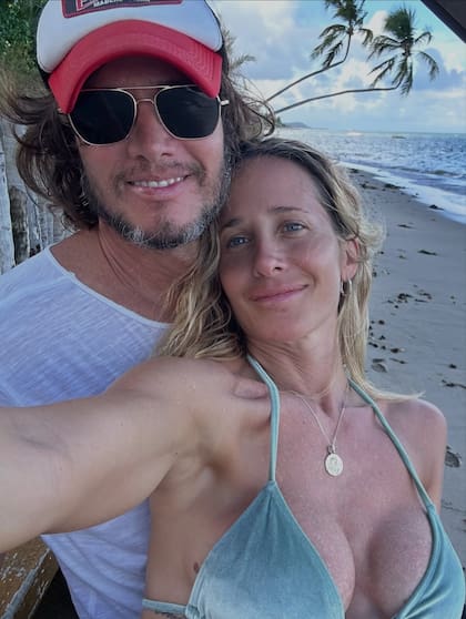 Abrazo bajo la sombra tropical junto al mar, donde la pareja se mostró sonriente y distendida