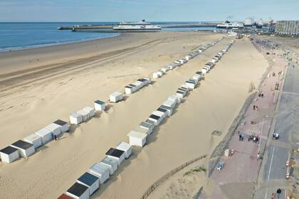Una vista aérea de un ferry que sale de la costa de Calais mientras la gente camina sobre el dique marino