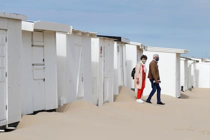 Una pareja con barbijos visita los refugios de playa en Calais, Francia