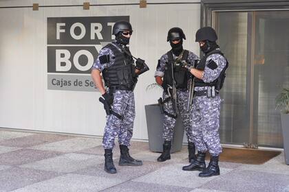 Tres efectivos policiales comenzaron a llevar los paquetes hacia un camión blindado de custodia de valores, que envolvían millones de dólares del sindicalista argentino
