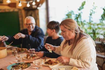 Abuelos latinoamericanos felices cenando con su nieto en el patio de su casa