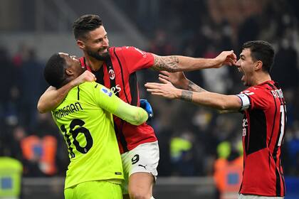 AC Milan's French goalkeeper Mike Maignan (L), AC Milan's French forward Olivier Giroud (C) and AC Milan's Italian defender Alessio Romagnoli (R) celebrate their victory at the end of the Italian Serie A football match between Inter Milan and AC Milan at the Giuseppe-Meazza (San Siro) stadium in Milan on February 5, 2022. (Photo by Isabella BONOTTO / AFP)