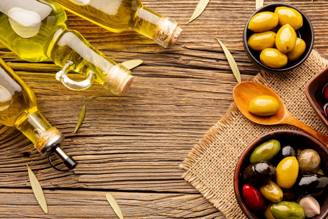 Botellas y frascos de aceite de oliva junto a aceitunas