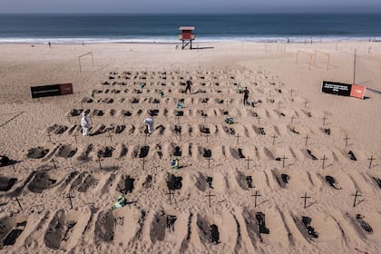 Activistas de la ONG brasileña Río de Paz cavan tumbas simuladas en la playa de Copacabana como protesta contra el mal manejo de la pandemia en Brasil