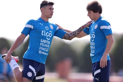 Adam Bareiro elonga con Matías Galarza durante una práctica de la selección paraguaya antes de viajar a la Argentina