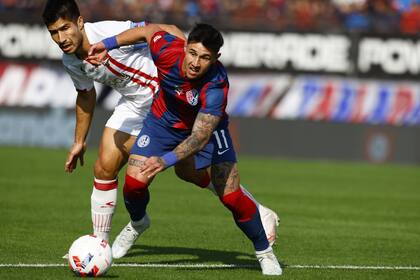 Adam Bareiro intenta desprenderse de la marca de Luciano Lollo; el delantero de San Lorenzo fue reemplazado en el segundo tiempo por Andrés Vombergar