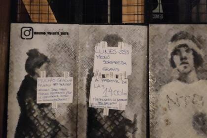 Adrin pega carteles en la puerta de su local para anunciar las novedades