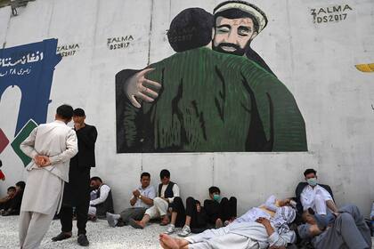 Un mural insta a la fraternidad entre afganos, mientras decenas de personas aguardan cerca de la embajada francesa en Kabul posiblemente en busca de un salvoconducto 
